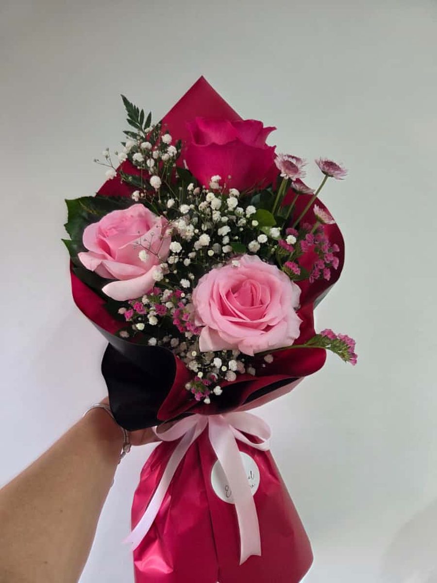 Ramo de tres rosas rosadas y fucsia con paniculata en papel rojo