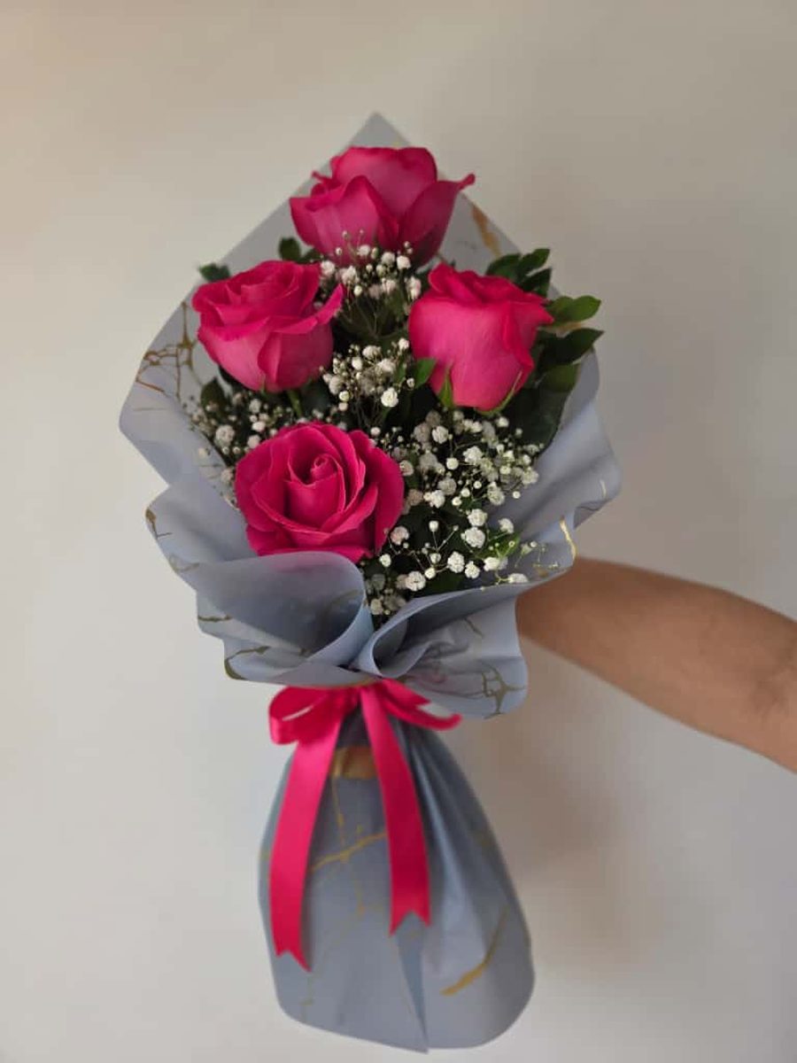 Ramo de cuatro rosas fucsia con paniculata en papel gris con vetas doradas