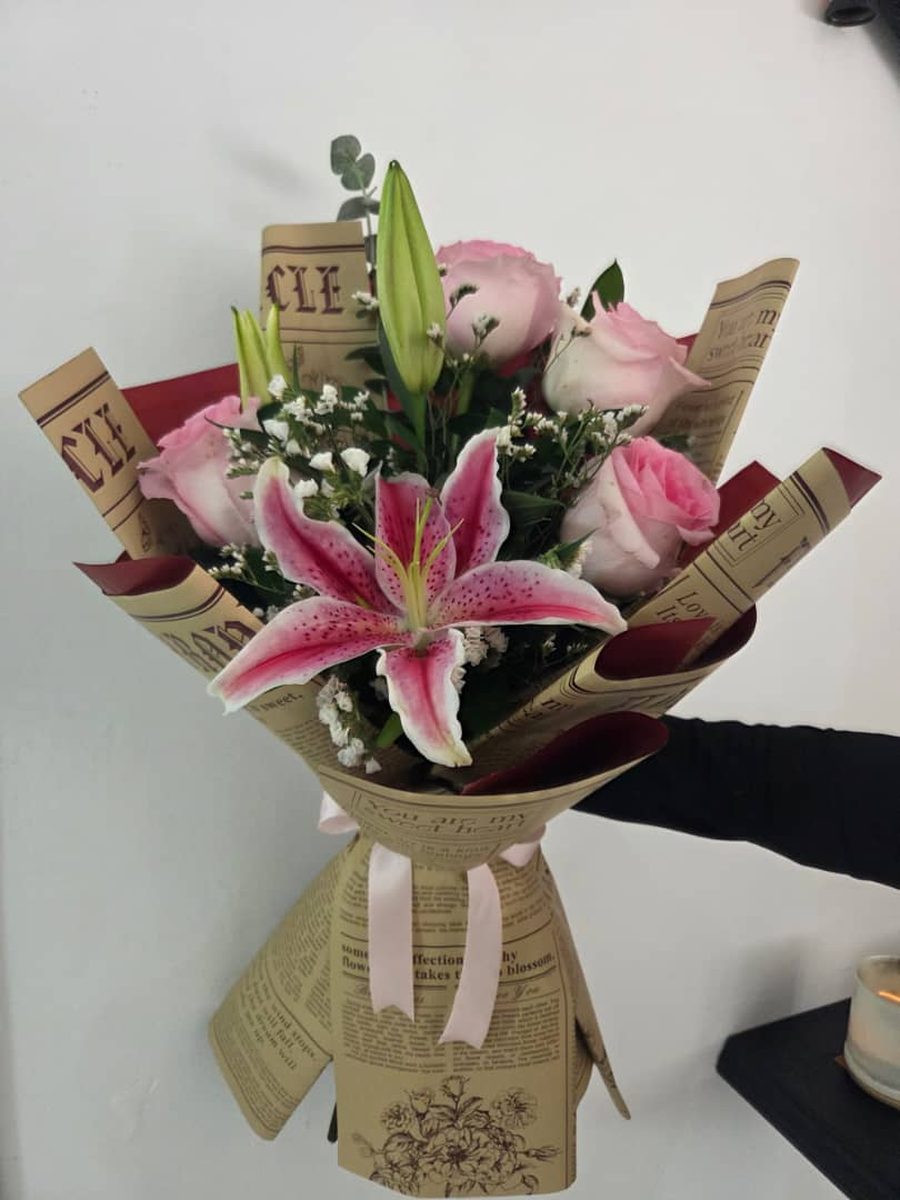 Ramo de lirio rosado y rosas rosadas envuelto en papel kraft estampado