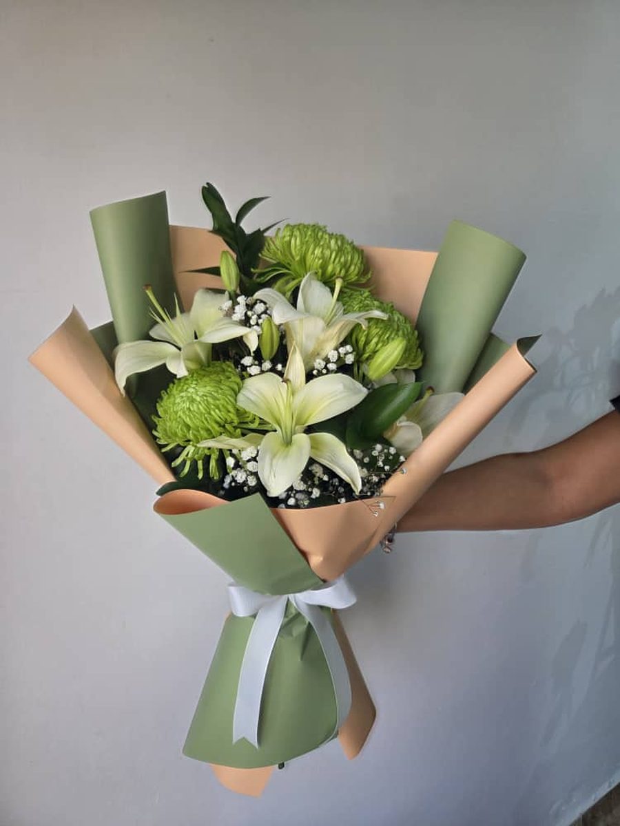 Ramo de lirios blancos y crisantemos verdes en papel verde y durazno