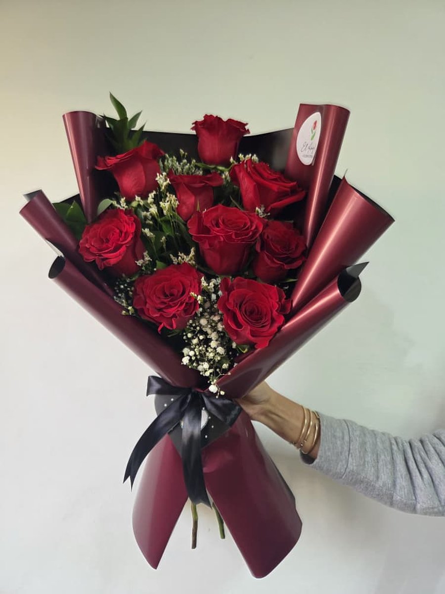 Ramo de rosas rojas con paniculata en papel vino con lazo negro