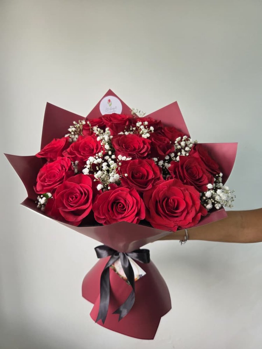 Ramo grande de rosas rojas con paniculata en papel rojo carmín con lazo negro
