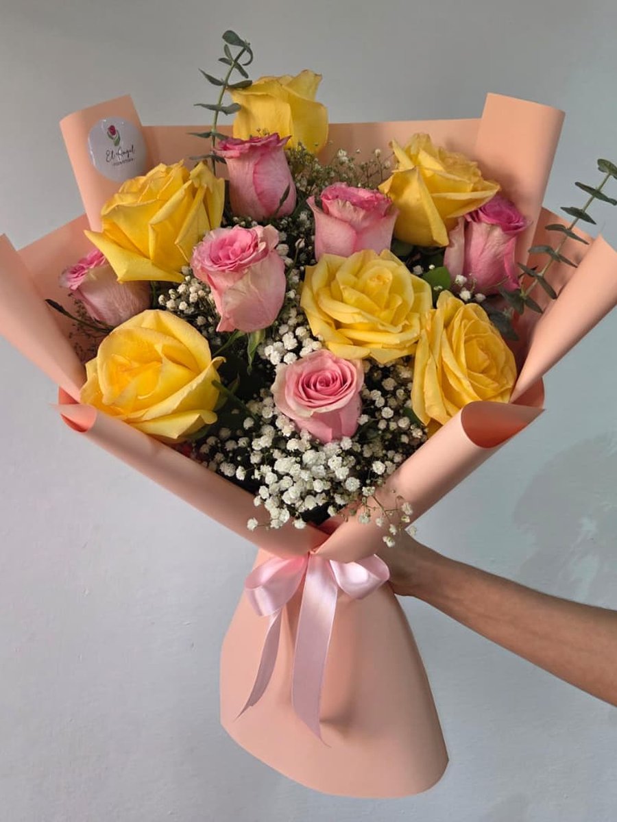 Ramo de rosas amarillas y rosadas con paniculata y eucalipto en papel durazno con lazo rosa