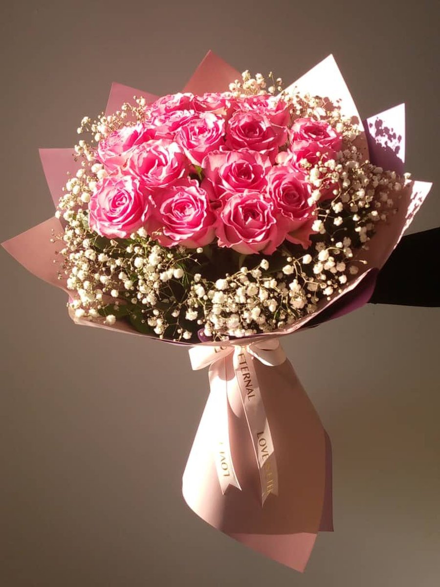 Ramo grande de rosas rosadas rodeadas de paniculata en papel rosa con lazo