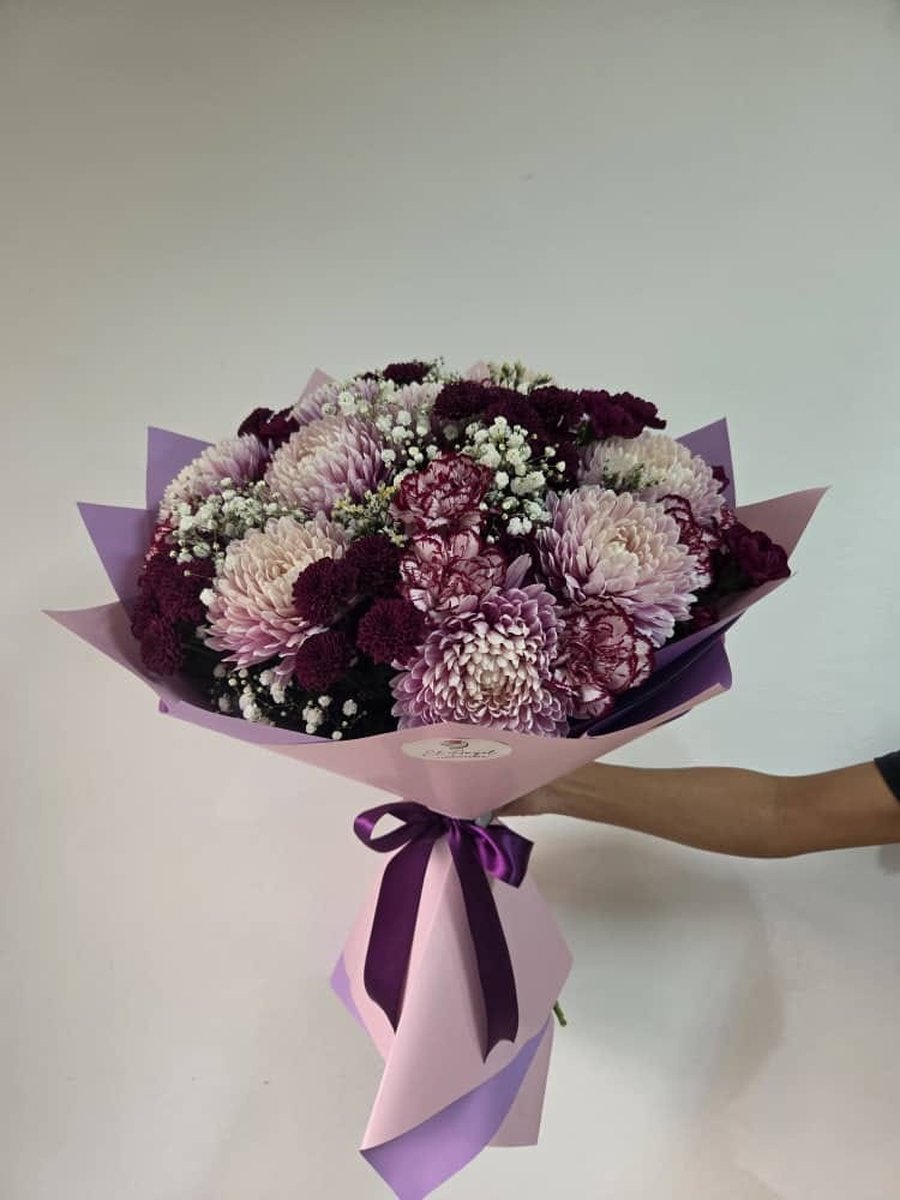 Ramo de crisantemos violeta y lila con paniculata en papel lila con lazo morado
