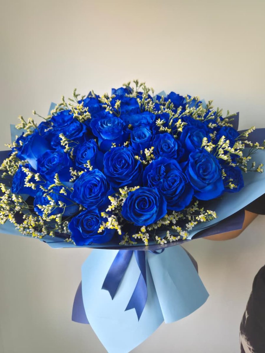 Ramo grande de rosas azules con solidago amarillo en papel celeste con lazo azul marino