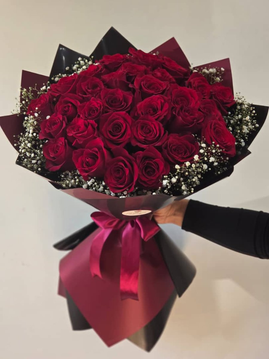 Ramo grande de rosas rojas con paniculata en papel negro con lazo vino